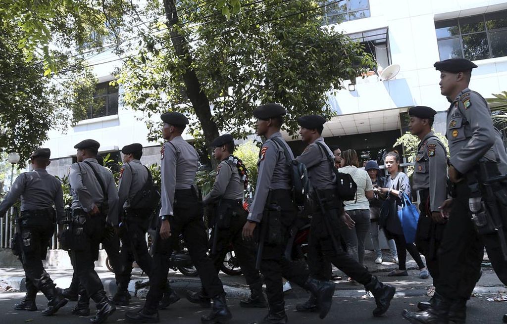 Sejumlah polisi melintas di depan pagar Gedung Lembaga bantuan Hukum Indonesia, Jakarta, Senin (18/9). Paska penyerangan oleh massa aksi sehari sebelumnya, polisi masih berjaga di sekitar gedung untujk mencegah aksi susulan.