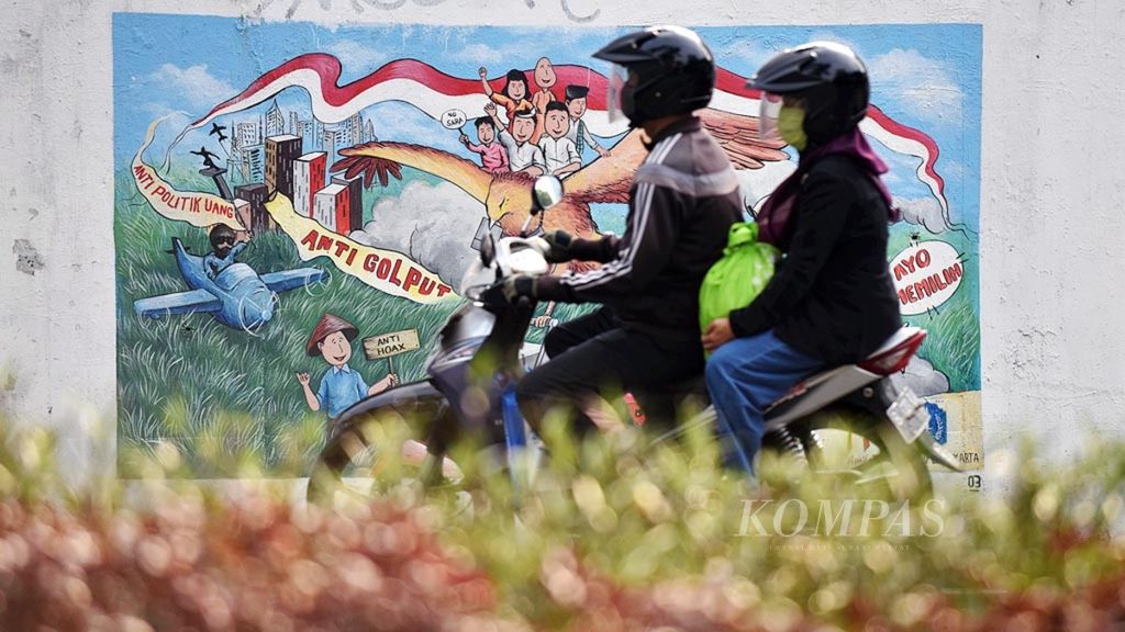 Warga melintasi mural Komisi Pemilihan Umum yang mengajak peran masyarakat untuk tidak golput dan melawan politik uang dalam pemilu di kawasan Dukuh Atas, Jakarta, Senin (13/7/2020). 
