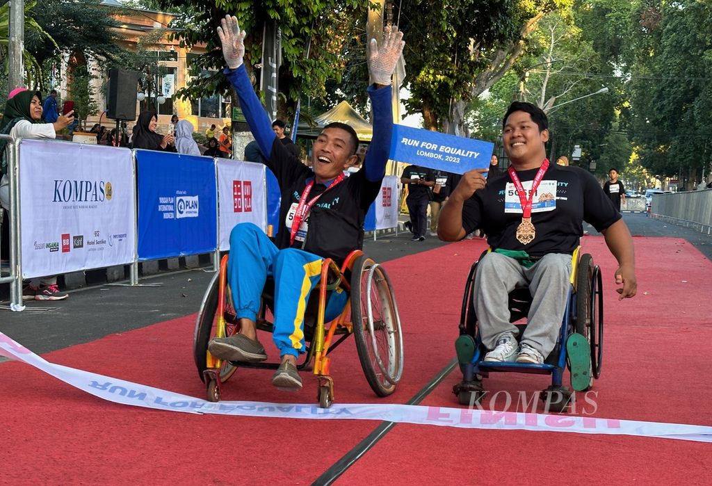 Dua peserta yang menggunakan kursi roda bergembira saat tiba di garis finis pada kegiatan lari dan jalan gembira bersama dengan tema "Run For Equality" di Mataram, Nusa Tenggara Barat, Minggu (30/7/2023) pagi. 