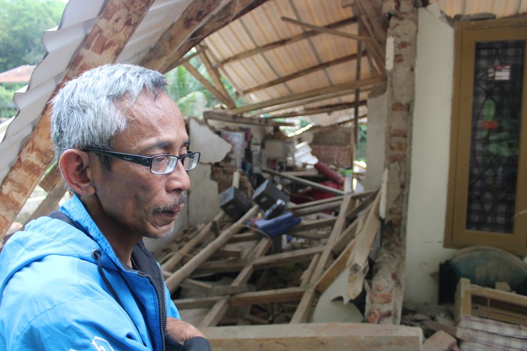 Salah satu warga berdiri di sebelah rumahnya yang rusak berat akibat gempa di Kelurahan Cipameungpeuk, Kecamatan Sumedang Selatan, Kabupaten Sumedang, Jawa Barat, Senin (1/1/2024). Rumah tersebut ambruk akibat gempa berkekuatan M 4,8 yang melanda Sumedang, Minggu (31/12/2023) pukul 20.34.