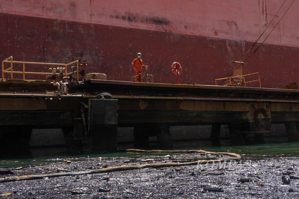 Pekerja mengamati limbah minyak hitam yang menggenang di galangan kapal PT Pax Ocean, Kota Batam, Kepulauan Riau, Kamis (1/12/2022).