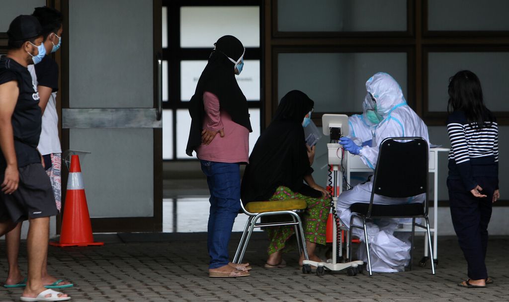 Petugas medis dengan alat pelindung diri memeriksa kondisi pasien Covid-19 dengan status orang tanpa gejala yang beraktivitas pagi di luar saat menjalani isolasi mandiri, di Stadion Patriot Candrabhaga, Kota Bekasi, Jawa Barat, Rabu (27/1/2021). 