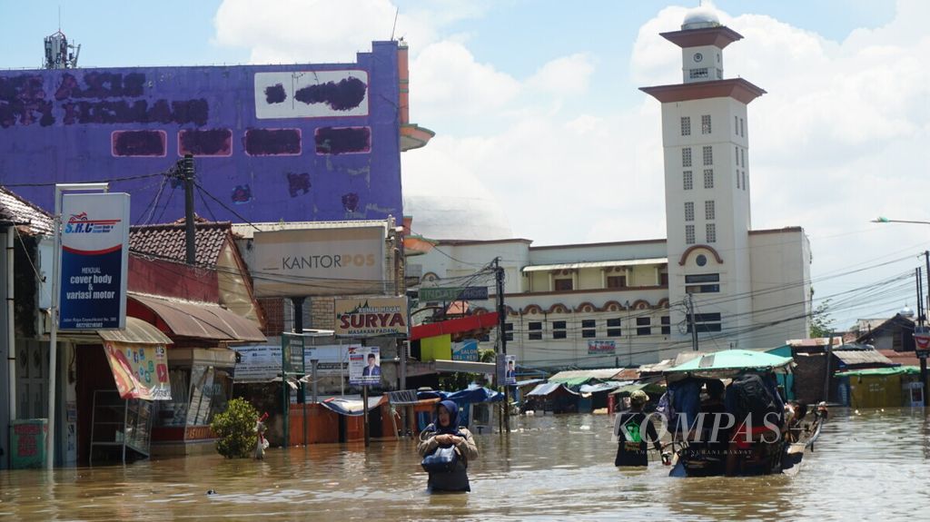 Warga berusaha melintasi banjir yang merendam Kecamatan Dayeuhkolot, Kabupaten Bandung, Kamis (4/4/2019).