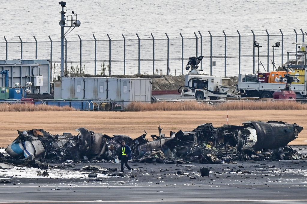 Seorang pejabat melihat puing-puing pesawat penjaga pantai Jepang di landasan Bandara Internasional Haneda, Tokyo, Jepang, pada 3 Januari 2024. 