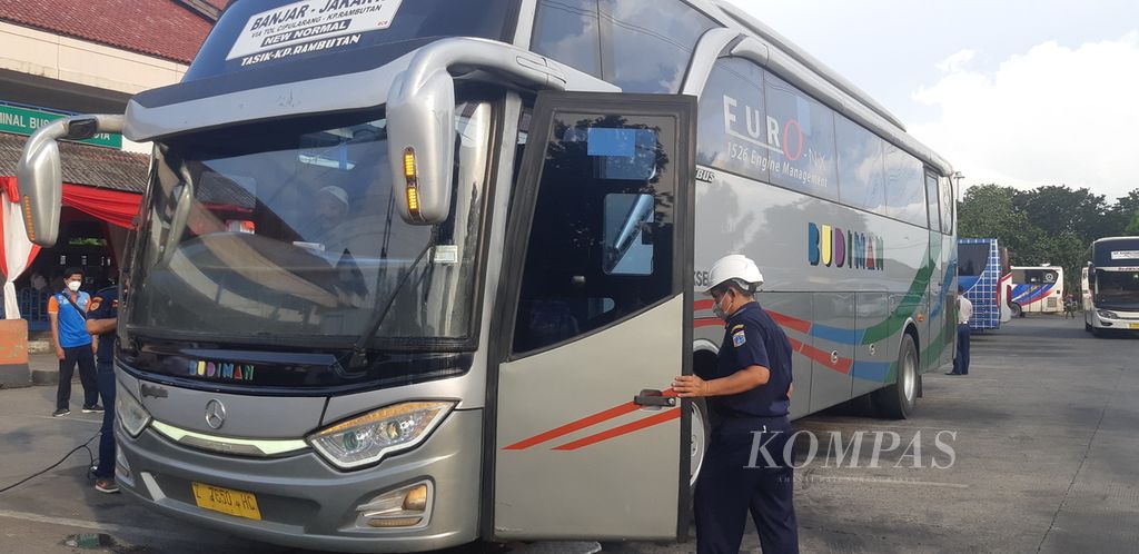 Petugas dinas perhubungan melakukan pengecekan fisik terhadap sebuah bus yang akan menjalani uji KIR kelayakan jalan di Terminal Kampung Rambutan, Ciracas, Jakarta Timur, Minggu (9/4/2023) sore.