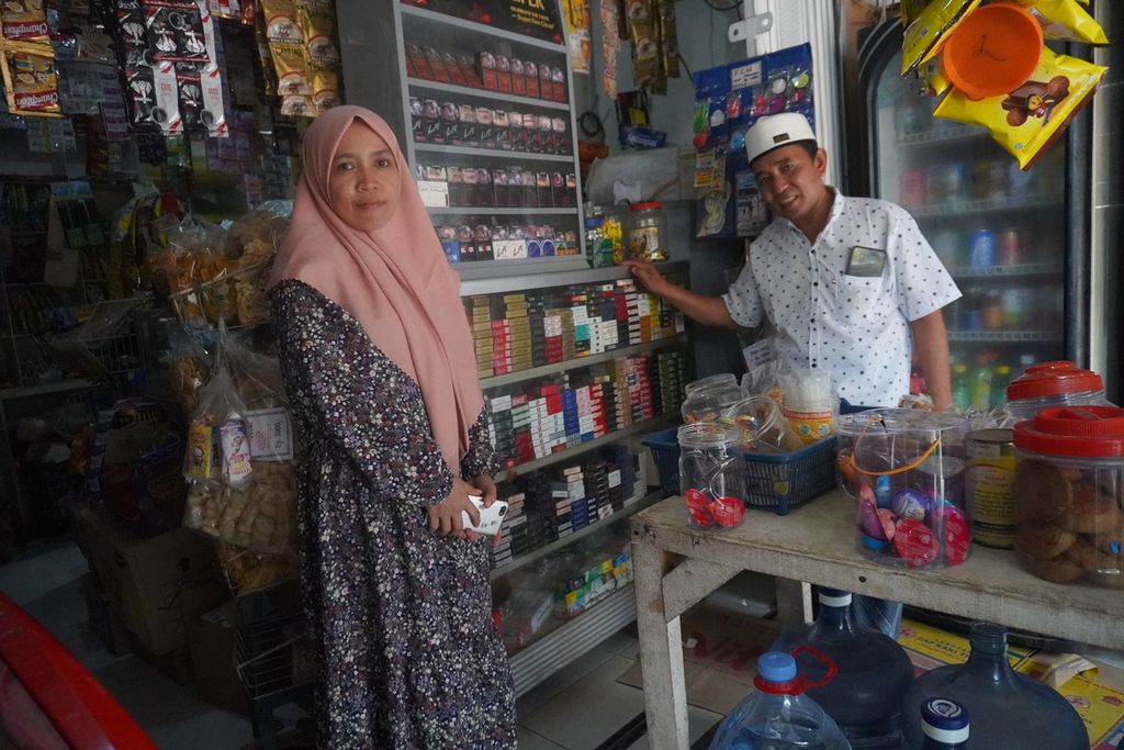  Fadlali (44) dan istrinya, Mas'odaturrahmaniyah (36), Kamis (10/11/2022), berdiri di depan salah satu dari empat toko kelontong mereka di kawasan Cijingga, Cikarang Selatan, Kabupaten Bekasi, Jawa Barat.