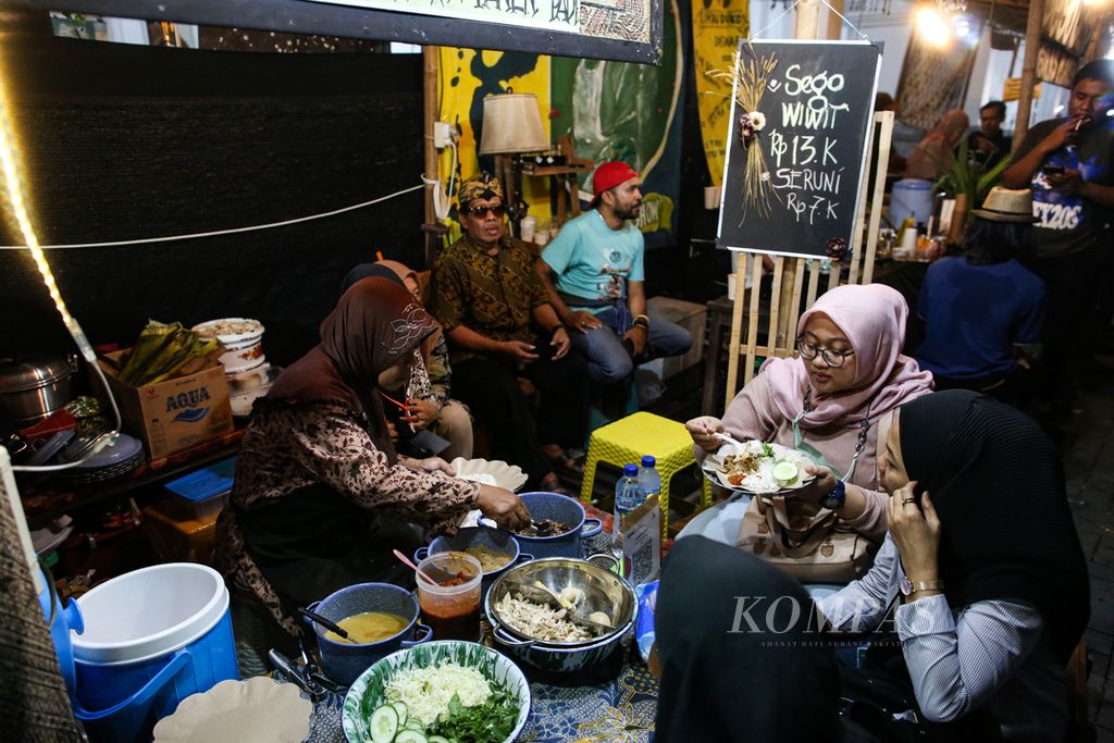 Pengunjung menikmati sego wiwit di Pasar Kangen Jogja 2023 di Taman Budaya Yogyakarta, Kota Yogyakarta, Rabu (2/8/2023) malam. Pasar Kangen menjadi destinasi wisata kuliner bagi warga Yogyakarta. 