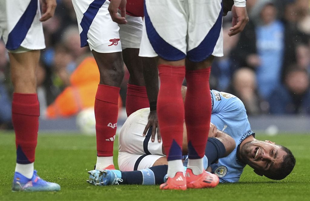 Gelandang Manchester City, Rodri, mengerang kesakitan setelah mengalami cedera saat laga Liga Inggris lawan Arsenal di Stadion Etihad, Manchester, Minggu (22/9/2024). Rodri harus absen satu musim akibat cedera robek ligamen lutut.