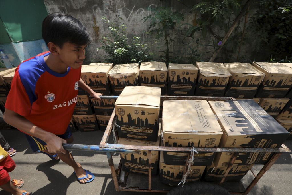 Warga menggunakan gerobak menyusuri jalanan kampung untuk mendistribusikan bantuan sosial Pemprov DKI di Kelurahan Palmeriam, Kecamatan Matraman, Jakarta Timur, Senin (27/7/2020).