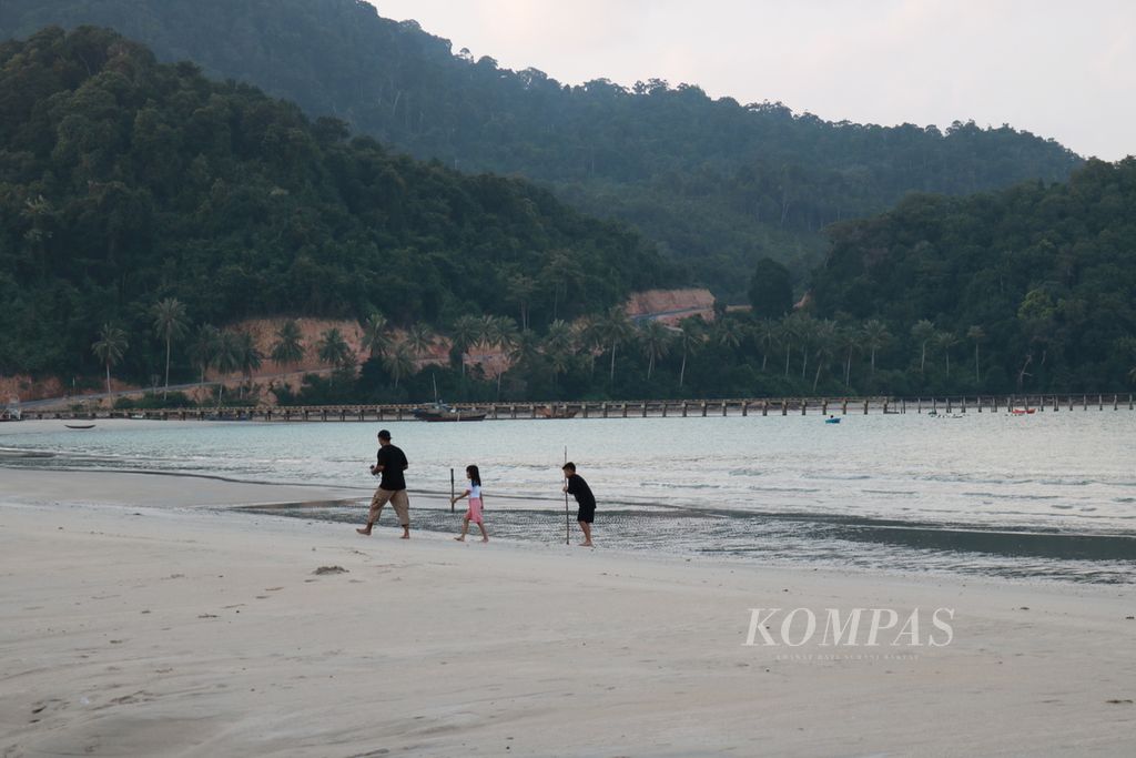 Seorang ayah bermain bersama kedua anaknya di Pantai Padang Melang, Pulau Jemaja, Anambas, Kepulauan Riau, Rabu (24/7/2024). Pantai dengan ombaknya yang tenang dan tanpa karang menjadi daya tarik sehingga masyarakat dapat bermain di pantai dengan aman.