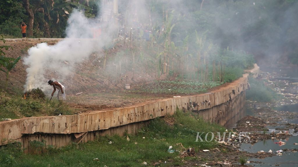 Warga membakar rumput kering di pinggir Sungai Ciliwung yang surut di Cawang, Kramat Jati, Jakarta Timur, Jumat (25/8/2023). Pembakaran sampah juga menjadi penyumbang polusi udara.
