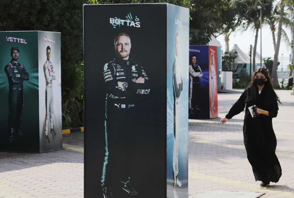 Perempuan tanpa kerudung melintas dekat poster balapan mobil GP Jeddah, Arab Saudi pada Desember 2021. Kerudung bukan lagi bagian busana wajib perempuan Arab Saudi.