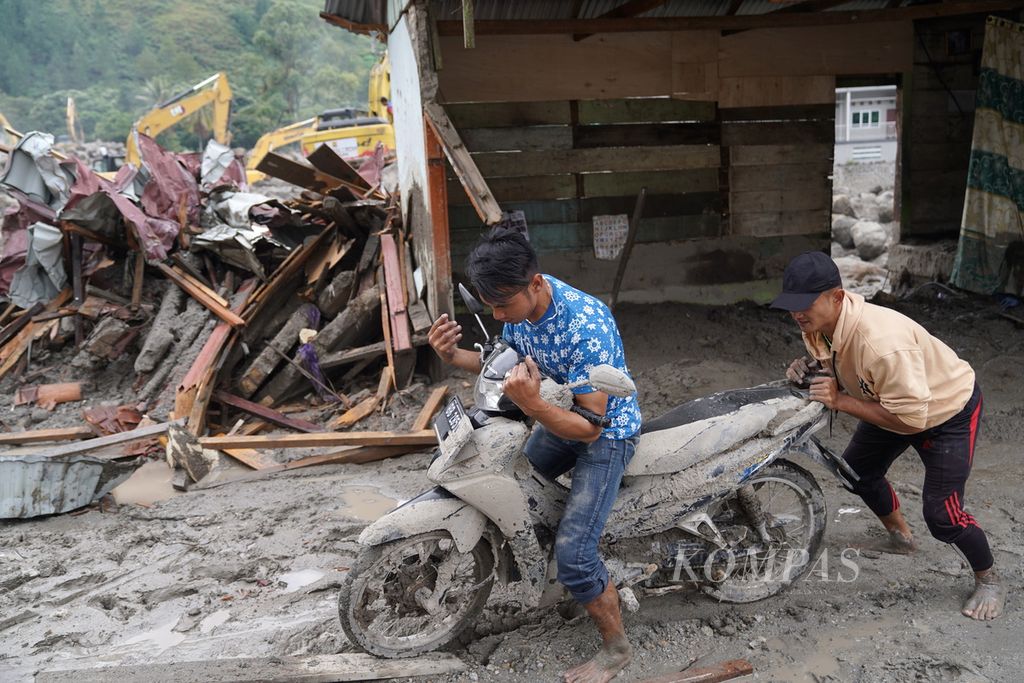 Warga menyelamatkan sepeda motor yang sebelumnya tertimbun lumpur dampak banjir bandang di Desa Simangulampe, Kecamatan Baktiraja, Kabupaten Humbang Hasundutan, Sumatera Utara, Rabu (6/12/2023). Bencana ini menelan 2 korban jiwa dan 10 orang lainnya masih hilang. Selain menimbulkan korban jiwa, 14 rumah warga hilang tersapu banjir dan 21 rumah lainnya rusak berat. 