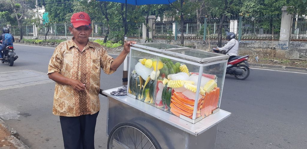 Marso, penjual buah potong keliling, menjajakan barang dagangannya di pinggir Jalan Tentara Pelajar, Jakarta Selatan, Jumat (21/8/2020). 