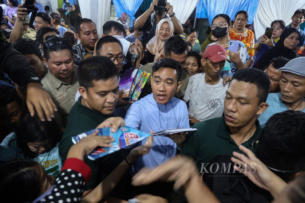 Calon wakil presiden nomor urut 2, Gibran Rakabuming Raka, membagikan buku kepada warga di Jalan Rawa Bebek 1, Penjaringan, Jakarta Utara, Jumat (1/12/2023). 