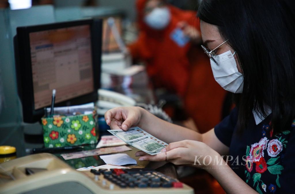 An officer checks the physical condition of US dollar bills exchanged by customers at the foreign exchange exchange at Valuta Inti Prima in Cikini, Central Jakarta, Tuesday (3/1/2023).