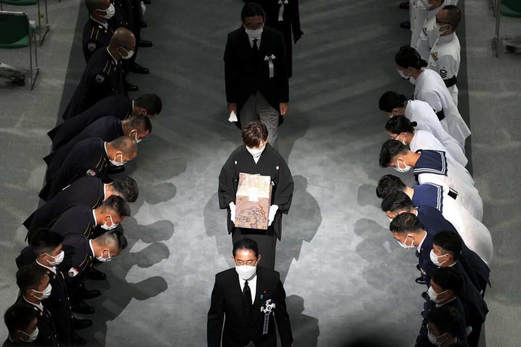 Akie Abe (tengah), istri mendiang mantan PM Jepang Shinzo Abe, membawa jambangan Abe, mengikuti langkah PM Fumio Kishida saat meninggalkan lokasi upacara pemakaman kenegaraan bagi Abe di Hall Nippon Budokan, Tokyo, Jepang, Selasa (27/9/2022). 
