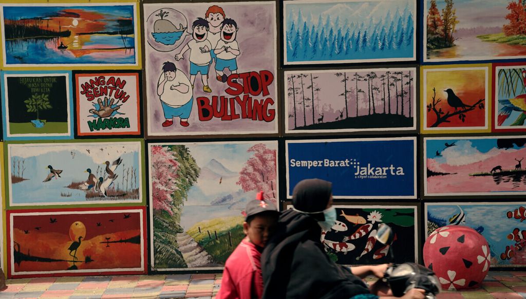 Ilustrasi. Seorang anak dibonceng ibunya melintasi mural bertema hentikan perundungan di Semper Barat, Cilincing, Jakarta Utara, Minggu (2/1/2022). Pemaksaan yang berujung pada diskriminasi dan perundungan harus dihentikan karena tidak menghargai hak asasi manusia.