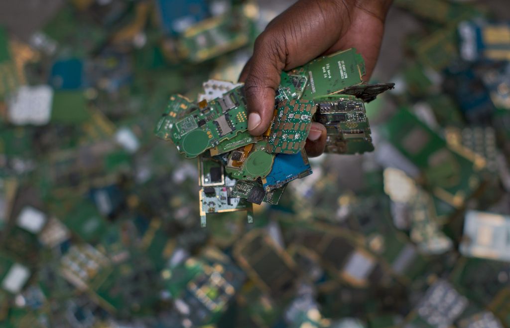 Seorang pekerja menunjukkan segenggam papan sirkuit cetak ponsel dari tumpukan untuk dimasukkan ke dalam karung dan didaur ulang di Machakos, Nairobi, Kenya, 18 Agustus 2014. 