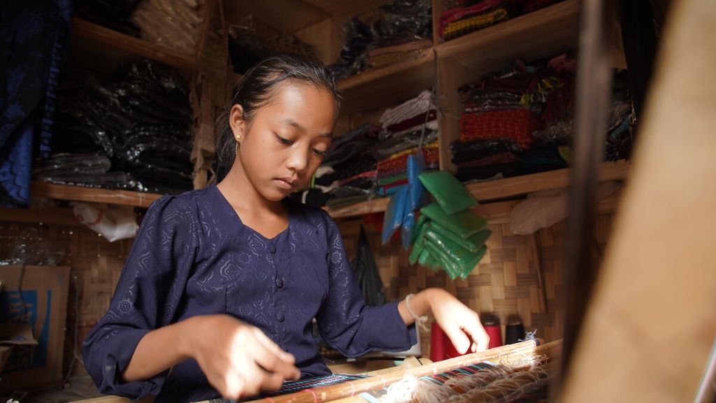 Ana (12), warga Baduy Luar, sedang menenun kain bermotif saut songket di warung milik bibinya, Jumat (28/10/2022). Anak kelahiran Kampung Balimbing, Desa Kanekes, Leuwidamar, Lebak, Banten, ini sudah belajar menenun sejak berumur tujuh tahun.