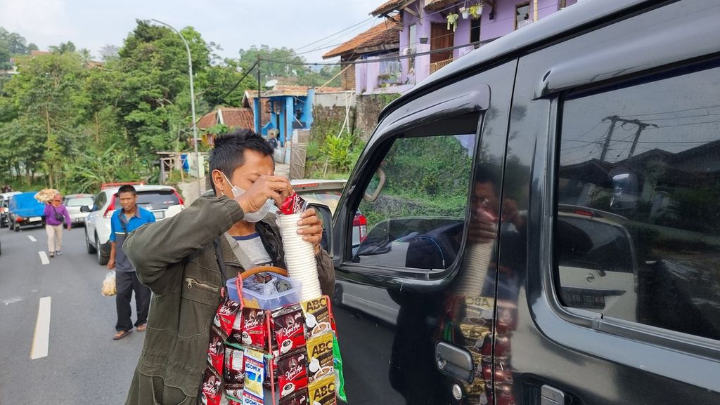 Seorang pedagang asongan meracik kopi kemasan di Jalur Nagreg, Kabupaten Bandung, Jawa Barat, Kamis (20/4/2023). Pedagang mulai meramaikan arus mudik tahun ini sejak H-7 Lebaran.