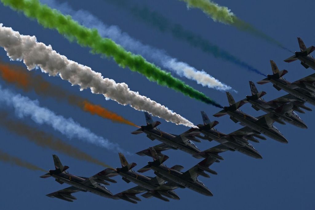 Pesawat dari tim aerobatik Angkatan Udara Italia melintas di atas Sirkuit Mugello saat balap MotoGP seri Italia, Minggu (11/6/2023). Pesawat menyemburkan asap tiga warna yang merupakan lambang bendera Italia. 