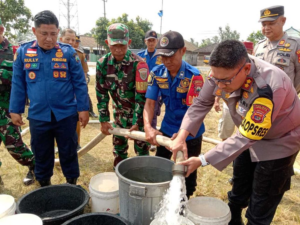 Kapolres Lampung Selatan Ajun Komisaris Besar Yusriandi Yusrin bersama petugas Dinas Damkar dan Penyelamatan Lampung Selatan menyalurkan air bersih untuk warga Desa Babatan, Kecamatan Katibung, Lampung Selatan, Selasa (3/9/2024). 