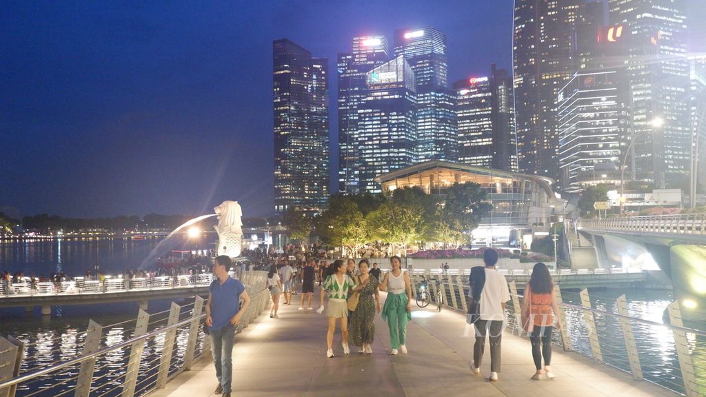 Wisatawan dari berbagai negara melewati Jubilee Bridge, jembatan penyeberangan yang membentang di atas Sungai Singapura, Selasa (16/4/2024) malam.