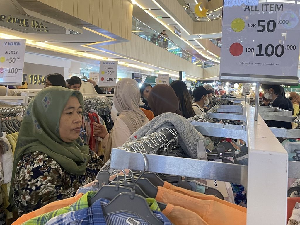 Ummu Khalifah (56) memilih baju yang ditawarkan dengan harga cuci gudang di Mal Plaza Blok M, Jakarta Selatan, Rabu (12/4/2023).