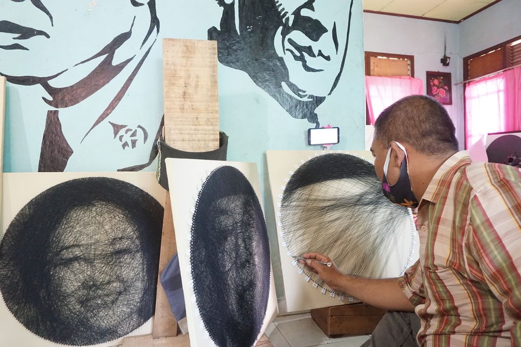 Surip (45), pegiat <i>string art</i>, sedang mengerjakan karya seni dari benang dan paku di rumahnya di Desa Haduyang, Kecamatan Natar, Kabupaten Lampung Selatan, Lampung. Minggu (14/3/2021).