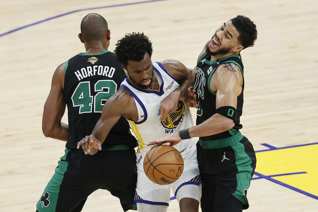 Pemain Golden State Warriors Andrew Wiggins (tengah) berusaha menembus adangan dua pemain Boston Celtics Al Horford (42) dan Jayson Tatum pada paruh kedua gim ke lima Final NBA di Chase Center, San Francisco, Amerika Serikat, Selasa (14/6/2022) pagi WIB. 
