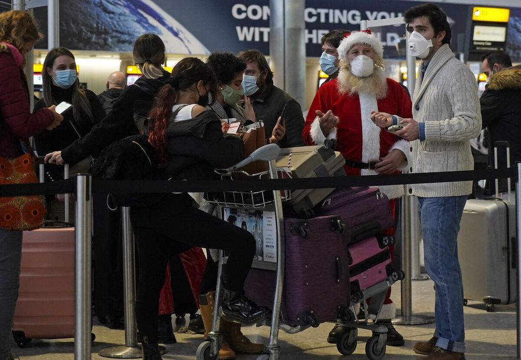 Calon penumpang yang mengenakan masker menunggu di aula keberangkatan di Terminal 2 Bandara Heathrow, London, Inggris, 21 Desember 2020. Penerbangan di Inggris terhambat setelah sejumlah negara melarang kedatangan pelancong dari Inggris akibat lonjakan kasus Covid-19 Omicron di Inggris.