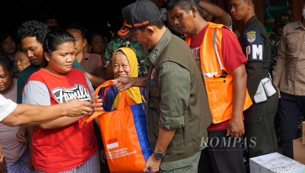 Kepala BNPB Suharyanto (bertopi) memberikan bantuan makanan cepat saji kepada pengungsi banjir di Kelurahan Gandekan, Kota Surakarta, Jateng, Sabtu (18/2/2023).
