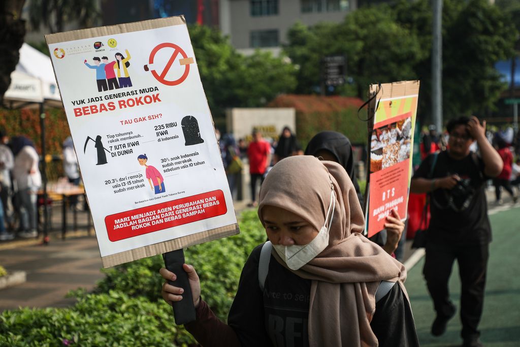Sukarelawan membawa poster tentang bahaya rokok, dalam kegiatan Plogging Cigarette Butt di kawasan Bundaran HI, Jakarta, Minggu (28/5/2023).