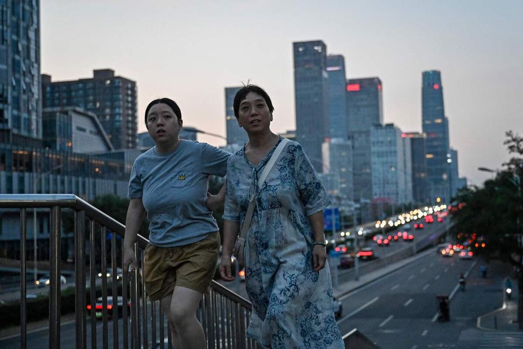 Warga berjalan kaki di sebuah jembatan penyeberangan di Beijing, China, 23 Juli 2023. 