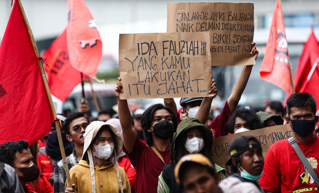Massa buruh dari Kongres Aliansi Serikat Buruh Indonesia (KASBI) memperlihatkan poster bernada sindiran kepada Menteri Ketenagakerjaan Ida Fauziyah saat berunjuk rasa di depan Kementerian Ketenagakerjaan, Jakarta, Rabu (23/2/2022).