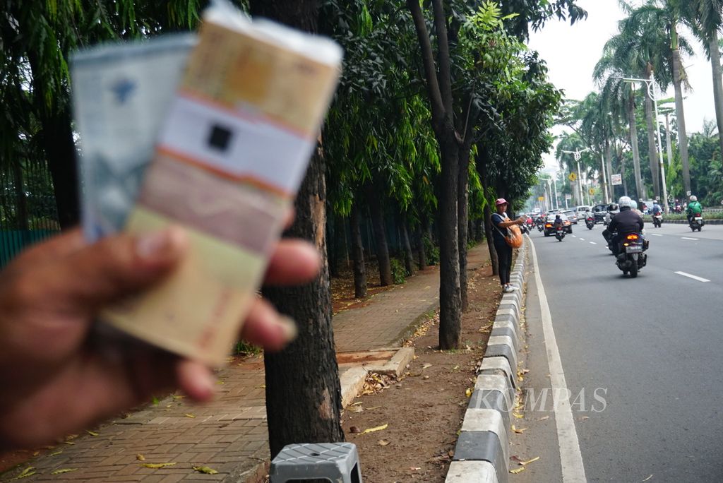 Seorang penjaja jasa penukaran pecahan uang kertas berdiri di tepi jalan di daerah Pondok Indah, Jakarta Selatan, Selasa (18/4/2023). Hampir semua penjaja jasa penukaran uang tersebut adalah perantau Batak dari Sumatera Utara.