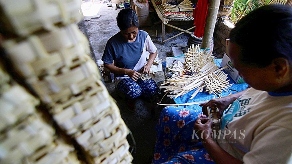 Zaenab (kiri) dibantu Kosiah membuat<i> godhong</i> atau wadah ikan dari anyaman bambu di Dusun Krajan, Desa Kebaman, Banyuwangi, Jawa Timur, Selasa (9/10/2018). Dengan modal bambu seharga Rp 15.000, mereka membuat 1.000 <i>godhong </i>senilai Rp 120.000.