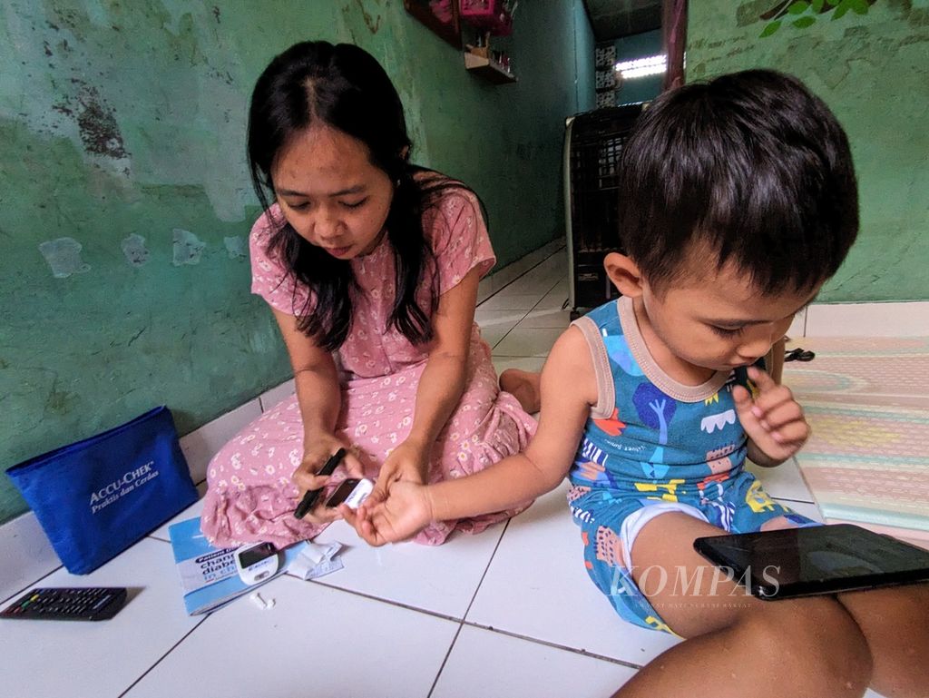 Alif (4) dicek kadar gulanya oleh ibunya, Ayu (30), saat ditemui di rumah mereka di Cibinong, Kabupaten Bogor, Jawa Barat, pada Senin (3/4/2023). Sebagai penyandang diabetes, Alif dicek kadar gula darahnya hingga tujuh kali sehari untuk mengontrol kadar gula darahnya. 