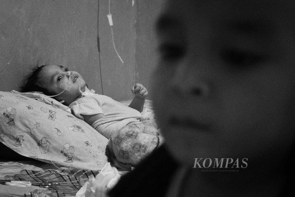 Zidan (5) menunggui adiknya, Nasifa (3), yang terbaring lemah di rumah mereka di Kota Batam, Kepulauan Riau, Rabu (14/6/2023).