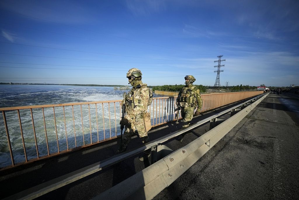 Tentara Rusia berpatroli di dam PLTA Kakhovka di Kherson, Ukraina selatan, 20 Mei 2022. Moskwa menyatakan bahwa Ukraina merencanakan serangan atas dam tersebut. Kyiv menuduh sebaliknya. Pada akhirnya, dam itu jebol karena serangan yang dilancarkan salah satu pihak pada 6 Juni 2023. Rusia-Ukraina saling tuding. 