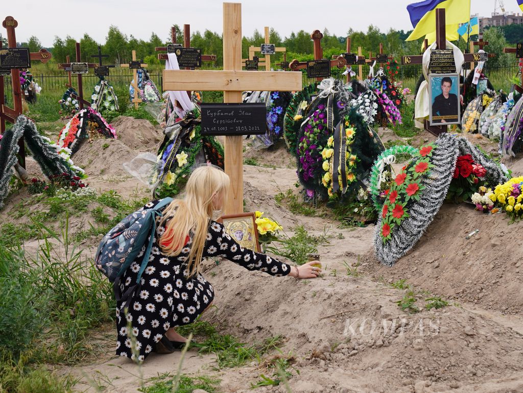 Seorang warga bersimpuh di pemakaman umum di Bucha, Ukraina, Juni 2022. 