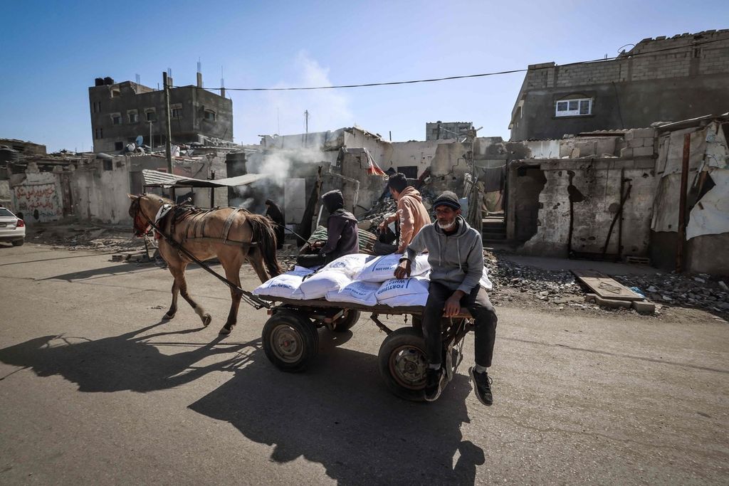 Warga Palestina mengangkut karung-karung tepung yang didistribusikan PBB di kamp pengungsi Rafah di Jalur Gaza selatan, Kamis (21/3/2024). 