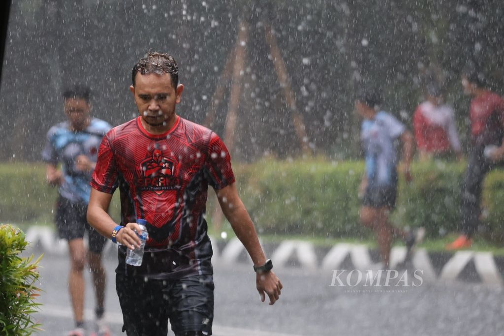 Para peserta menembus hujan saat mengikuti Run the Ground di kawasan Gelora Bung Karno, Jakarta, Sabtu (9/3/2024). Harian <i>Kompas</i> dan Lembaga Penjamin Simpanan menggelar acara lari Run the Ground sebagai pra-acara Monas Half Marathon 2024. Acara ini digelar bersama komunitas lari. Sebanyak 25 grup atau 125 pelari mengikuti acara ini. 