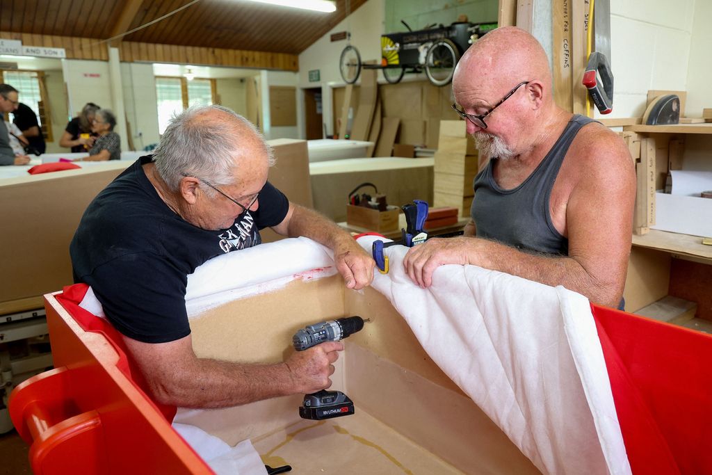 Foto pada 27 Februari 2024 memperlihatkan dua anggota Hawke’s Bay Coffin Club di Hastings, Selandia Baru, tengah mempersiapkan peti mati yang akan digunakan anggota kelompok atau diri sendiri. 