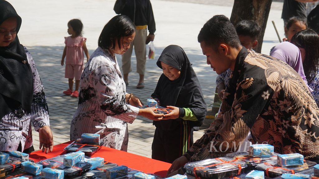 Guru membagikan sepaket makanan kepada para siswa dalam uji coba program makan bergizi gratis di SD Negeri Tugu 120 Surakarta, Kota Surakarta, Jawa Tengah, Kamis (25/7/2024). 