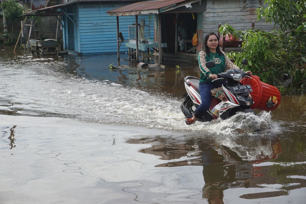 Warga Katinngan Hilir, Kabupaten Katingan, Kalimantan Tengah, Minggu (13/9/2020), menyusuri banjir akibat luapan SUngai Katingan. Setidaknya 21 kecamatan di Kalteng terendam banjir di empat kabupaten.
