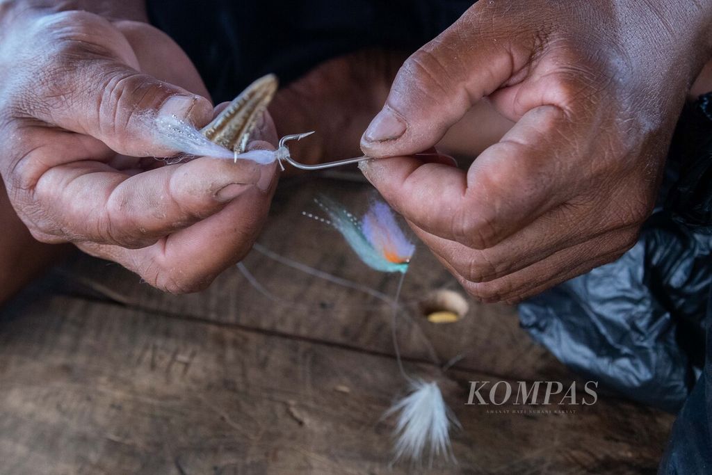 Rustam (48) menyiapkan umpan yang terbuat dari beberapa jenis benang untuk memancing ikan tongkol di perairan yang berjarak sekitar 45 kilometer di sebelah timur Pulau Natuna Besar, Kepulauan Riau, Sabtu (26/3/2022).