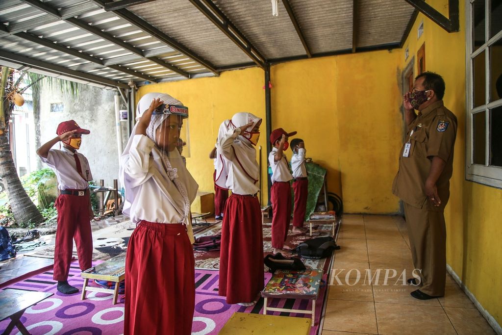 Suhendra (53), guru kelas III SDN Pondok Petir 2, Bojongsari, Depok, Jawa Barat, memimpin anak didiknya untuk hormat kepada bendera Merah Putih sebagai pengganti upacara bendera sebelum memulai mengajar secara tatap muka di teras rumah salah seorang wali murid, Senin (31/8/2020). 