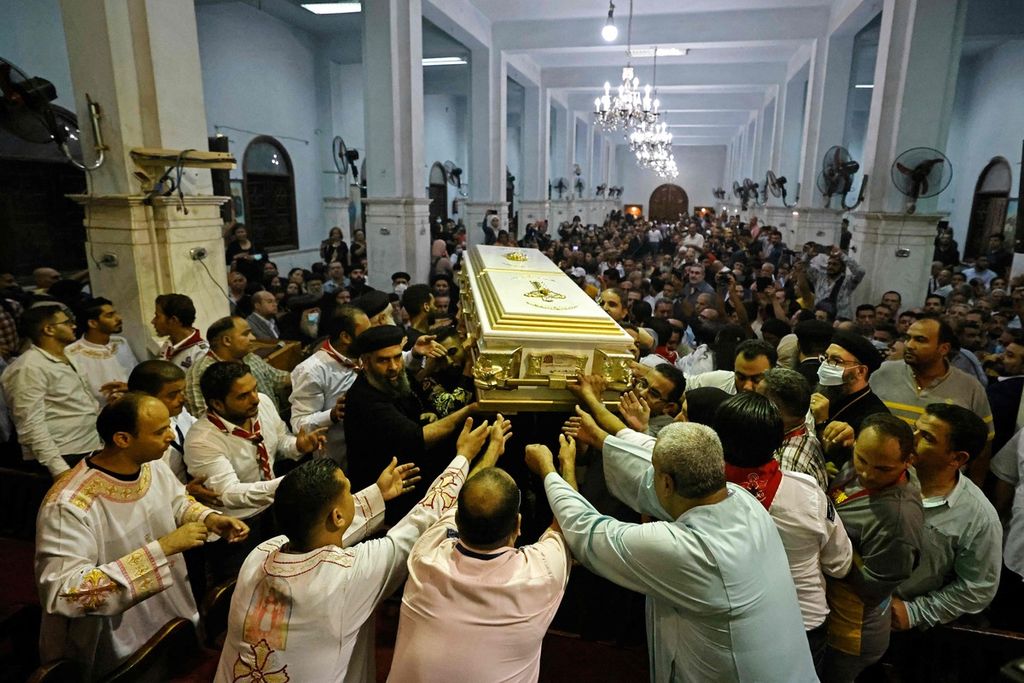 Umat yang berduka turut mengangkat peti berisi jenasah salah satu korban tewas dalam kebakaran di sebuah gereja Kristen Koptik di Giza, Mesir, MInggu petang (14/8/2022). Ratusan hadir memadati upacara pemakanan para korban.